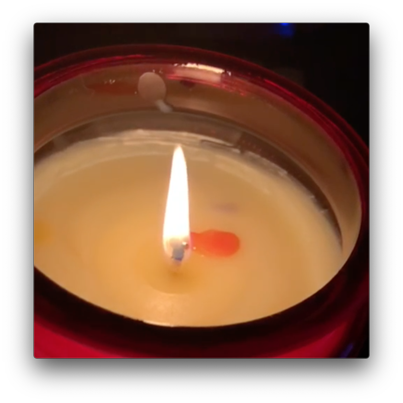 closeup of a lit candle red jar
